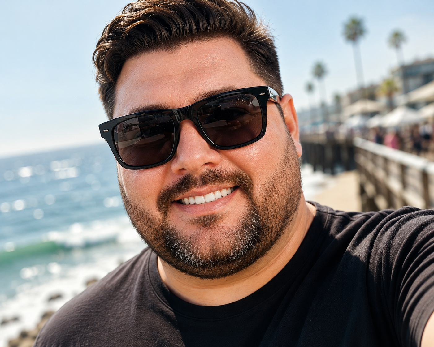 man with a big head wearing wide frame sunglasses at the beach